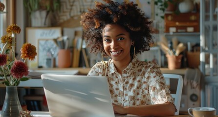 Wall Mural - A woman with curly hair is sitting at a table with a laptop in front of her