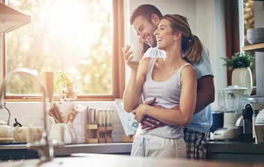 Canvas Print - Coffee, hug and laughing with couple in kitchen of home together for morning break or wellness. Funny, smile or tea with happy man and woman drinking fresh beverage in apartment for love or romance