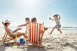 © Reese Coop/peopleimages.com - Family, children and playing at beach chair, vacation adventure and jump with bonding on summer journey. Parents, kids and excited for ocean freedom, energy and sunshine travel in Bali island