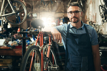 Wall Mural - Man, portrait and entrepreneur at work in bicycle repair shop or maintenance garage. Bike, mechanic and service with a professional confidence for startup, small business and workshop for fixing