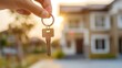 © May Chanikran - Hand holding a house key with home in the background, representing real estate, new home purchase, or property investment.