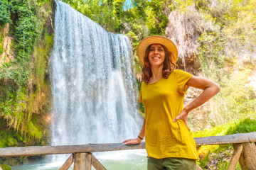 Wall Mural - Portrait of a female tourist with a hat looking at La Caprichosa waterfall in the Monasterio de Piedra Natural Park, Aragon, Spain