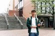 © EFStock - Portrait of smiling student guy standing on university campus building. Happy looking at the camera ready for lecture