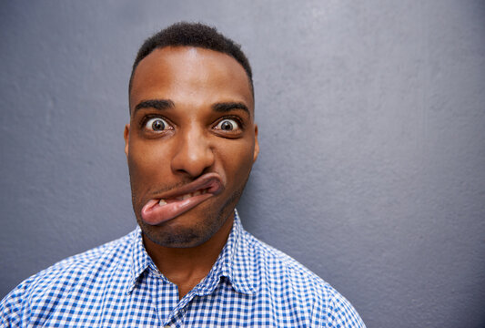 Goofy, funny and portrait of black man by wall for comic, playful or comedy joke expression. Silly, crazy and face of confident young African male person by gray background with mockup space.