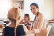 © Cecilie S W/peopleimages.com - Woman, children and talking at breakfast in kitchen for bonding, love and care with healthy nutrition in morning. Mother, girl and happy family with conversation, support and eating lunch at house