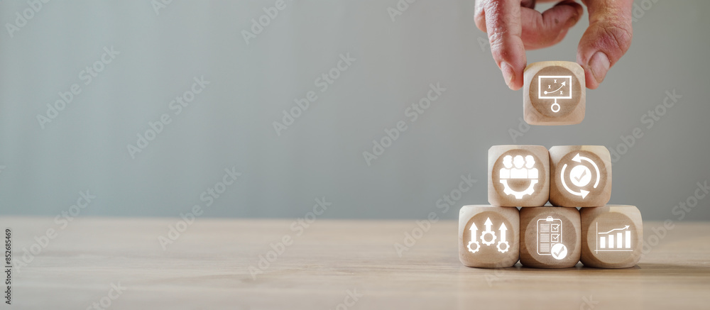 Hand stacking wooden blocks with business continuity icons, symbolizing ...