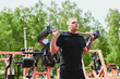© amixstudio - Caucasian male athlete trains legs on fitness equipment, outdoor workout in a summer park