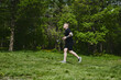 © amixstudio - Caucasian male athlete jogging outdoors in a summer park
