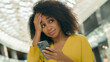 © Yuliia - African American woman looking smartphone mobile phone screen holding head bad news problem notification upset girl sad female worried anxiety frustrated online anxious broken deception shopping mall