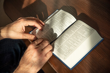 Wall Mural - Hands of man holding Holy Bible at home. Lifestyle, natural aesthetic light.