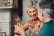 © Cecilie S W/peopleimages.com - Senior women, wine and relax with toast for retirement celebration, communication with happiness in house. Elderly, female people and alcohol drink in home with conversation, cheers for wellness