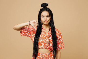 Wall Mural - Young sad dissatisfied displeased Latin woman she wearing orange casual clothes showing thumb down dislike gesture isolated on plain pastel light beige background studio portrait. Lifestyle concept.