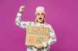 © ViDi Studio - Young lesbian woman she wear pink animal clothes hold cardboard card with LGBTQ rights title text, clench fist isolated on plain purple background studio portrait. Pride day June month love concept.