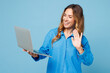 © ViDi Studio - Young happy IT woman wear shirt casual clothes hold use work on laptop pc computer waving hand get video call isolated on plain pastel light blue cyan background studio portrait. Lifestyle concept.