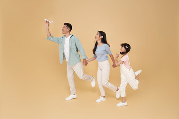 Happy fun asian family vacation portrait. Father, mother and daughters ready for travel flight isolated on nude color background.