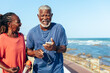 © (JLco) Julia Amaral - Senior African American couple laughing and listening to music on the coast
