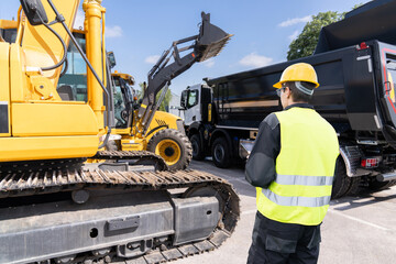 Aufkleber - Engineer in a helmet with a digital tablet stands next to construction excavators