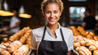 © XXX - Caucasian woman, an apprentice wearing apron and standing in a middle of a bakery with buns.