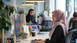 © Kafka - Professional hijabi woman working at her computer in a modern office, coworker blurred in the background