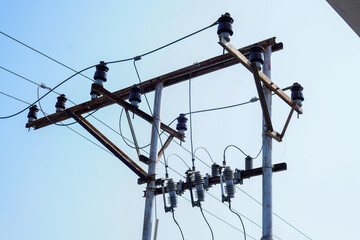 Concrete high voltage power electric pole with power lines and fuses against sky background