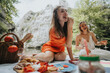 © qunica.com - Two friends having fun at a summer picnic in a scenic outdoor setting, enjoying food and drinks.