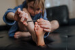 © shchus - Girl, child sitting in the room on the sofa, cutting her toenails with manicure scissors. Close-up photography, cosmetic procedure, self care concept.