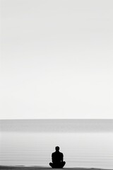 Fototapete - A man is sitting on the beach, looking out at the ocean. The sky is clear and the water is calm. The man is in a contemplative mood