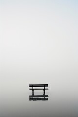 Fototapete - A bench is sitting in a lake with a cloudy sky in the background. The bench is the only object in the scene, and it is empty