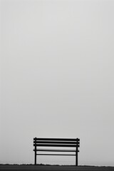 Fototapete - A bench is sitting on a grassy hillside. The sky is overcast and the bench is empty