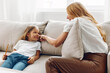 © SHOTPRIME STUDIO - Mother and daughter bonding on a cozy couch, sharing a heartwarming moment in a sunlit living room