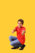 © Pixel-Shot - Little African-American boy showing thumbs-up on yellow background