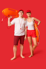 Wall Mural - Lifeguards with ring buoy and rescue tube on red background