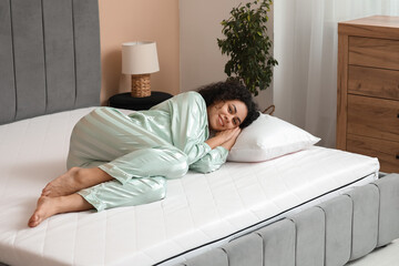 Sticker - Young African-American woman with pillow lying on soft mattress in bedroom