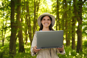 Wall Mural - Forester with laptop examining plants in forest