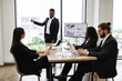 © sofiko14 - Business professionals in modern office having a meeting with presentation, discussing charts and data analysis. Concept of teamwork, corporate strategy, and business planning.