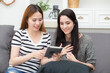 © NT_studio - Young woman and friends relax sitting on sofa share and discussion on digital tablet together in living room at home, two woman looking tablet about social media and conversation, lifestyle concept.
