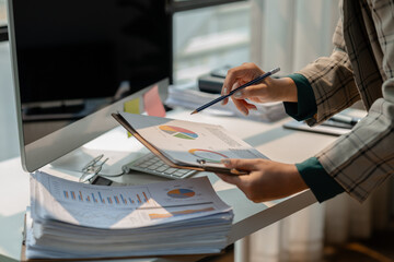 working in workplace on the desk with computer, female employee is looking on document, en entrepreneur is trying so hard to build startup company, finance department