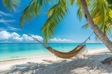 Hammock hanging from palm tree on white sand beach with turquoise water. 