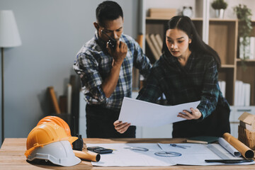 Asian young female architect discussing with japanese male building manager contractor for quality control site inspection and at house construction site in room under renovation project.