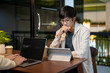 © bongkarn - A young Asian male student is focusing on his work on his digital tablet in a cafe co-working space.