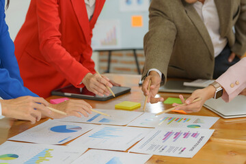 Wall Mural - Close-up of diverse businesspeople gathering at the office desk to discuss company financial paperwork at a meeting together, multiracial colleagues brainstorm work with documents at an office.