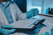 © kamiphotos - a scientist is working in laboratory and taking note of experiment result, paperwork has chemical's name on it, after research all sample and get result a chemist have to write it down on paper report