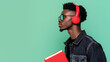© Luluraschi - cool senior high school black guy student wearing red headset and carrying a book, light aqua green background, space for copy text
