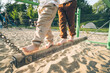 © Westend61 - Low section of boy and girl walking on balance beam in playground