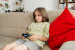 © Westend61 - Cute boy sitting on sofa and playing video game at home