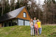 © Westend61 - Happy family standing together in front of modern house