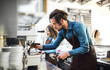 © Halfpoint - Two young baristas working in coffee shop, standing by counter, preparing coffe in machine. University students working part-time in cafe.