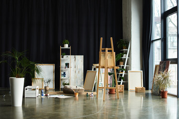 Wall Mural - A spacious studio with an easel and canvases, ready for a young artist to create.