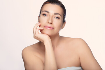 Wall Mural - Beautiful mid-aged woman with natural look, showcasing beauty and skincare concepts on a light background