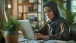 © Kafka - A focused and stylish hijabi woman immersed in her laptop in a contemporary office, working in finance.